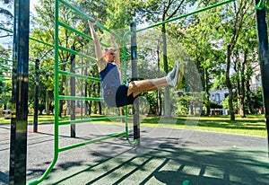 Young guy athlete exercising on sports equipment in the park