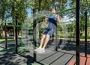 Young guy athlete exercising on sports equipment in the park