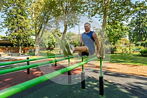 Young guy athlete exercising on sports equipment in the park