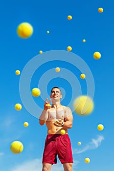 Young guy athlete juggles yellow balls outdoors. Concept sport. photo