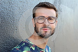 Young guy with a beard and mustache with glasses in a flowered or floral shirt posing on the street, fashion man, style, vintage