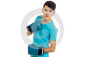 A young guy in a blue shirt and boxing gloves looks in camera