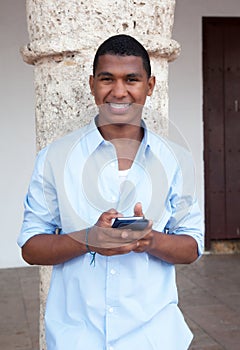 Young guy in a blue shirt typing message at phone