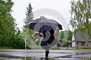 Young guy breakdance dancing in the rain with an umbrella