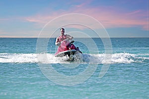 Young guy cruising on the caribbean sea on a jet ski