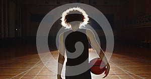 Young guy curly basketball player darkness silhouette getting ready light beam image serious shadow parquet hall sports