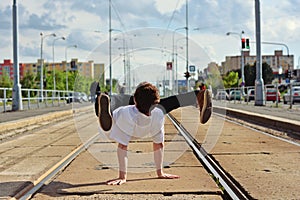 Young guy dancing breakdance on tramlines in the city