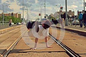 Young guy dancing breakdance on tramlines in the city