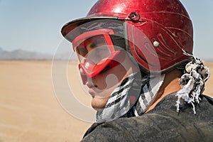 Young guy during desert excursion by quad - Man in helmet and adventure clothes in exotic scenarios - Concept of activity holiday,