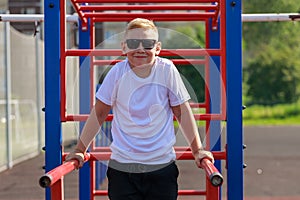 a young guy does push-ups on bars on a sports ground in the summer