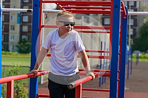 a young guy does push-ups on bars on a sports ground in the summer