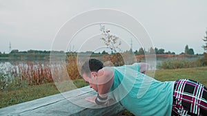 A Young Guy Does Push-Ups In The Early Morning In Nature Behind Lake Or A Quarry