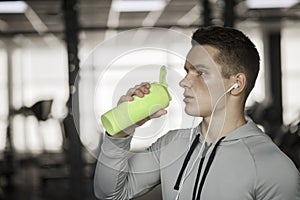 Young guy drinks sports nutrition in gym