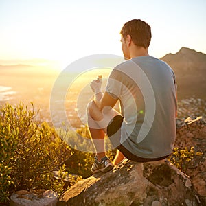 Young guy eating a protein bar at sunrise on a hike