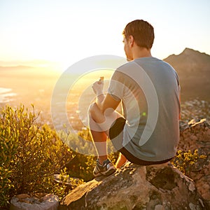 Young guy eating a protein bar at sunrise on a hike photo