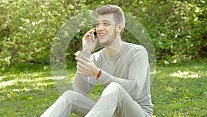 Young guy eats ice cream and talking on the phone in the park