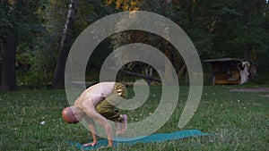Young guy engaged in yoga in the morning in the forest on the glade