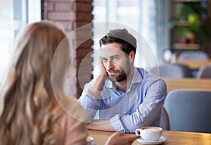 Young guy feeling bored on dull date at restaurant, disappointed in his partner