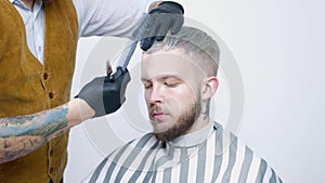 A young guy gets a haircut with hair scissors with a comb.
