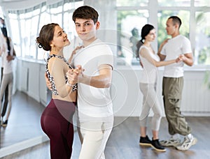 Young guy and girl dancing slow ballroom dance in studio