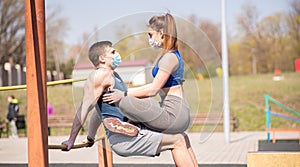 A young guy and a girl push up on the bars in medical masks during a pandemic