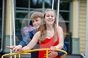 Young guy with a girl on a swing in the park