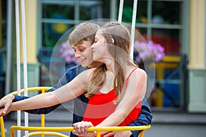 Young guy with a girl on a swing in the park