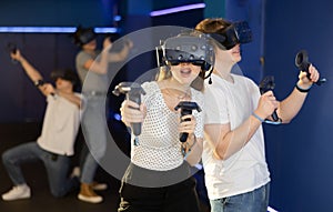 Young guy and girl in vr headset stand shoulder to shoulder interacting with digital interface