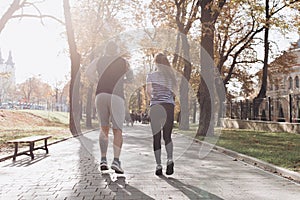 Young guy and girl working out. Fitness couple running together on sunny park. Man and woman at sport training together