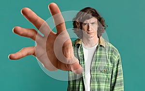 Young guy grabbing something on turquoise background