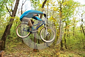 A young guy in a helmet flies landed on a bicycle after jumping from a kicker