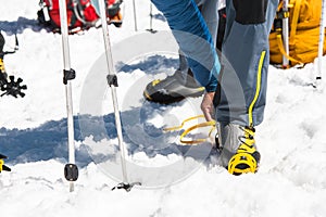 A young guy hiker dresses climbing Crampons over mountaineering shoes For walking through Glacier