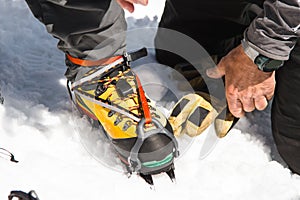 A young guy hiker dresses climbing Crampons over mountaineering shoes For walking through Glacier