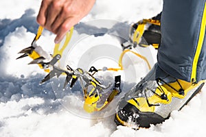 A young guy hiker dresses climbing Crampons over mountaineering shoes For walking through Glacier