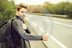 Young guy hitchhiking autostop with hand outdoor