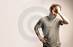 Young guy holding his head in a pensive pose. Model with a beard ponders problems and solutions. Concept of fear photo