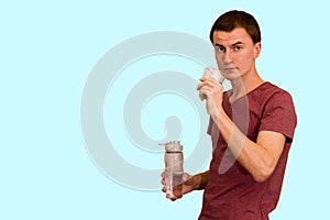 A young guy holds a bottle of water in his hand