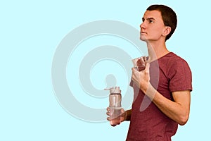 A young guy holds a bottle of water in his hand