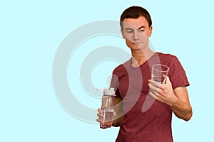 A young guy holds a bottle of water in his hand