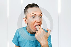 Young guy inserts two fingers in the mouth to induce vomiting photo