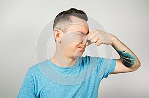 Young guy inserts two fingers in the mouth to induce vomiting, on a light background
