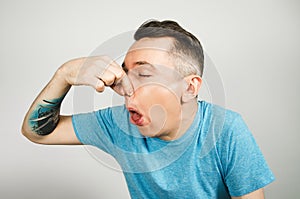 Young guy inserts two fingers in the mouth to induce vomiting, on a light background photo