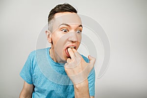 Young guy inserts two fingers in the mouth to induce vomiting, on a light background