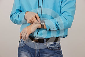 young guy in jeans and a blue shirt with watches on his arm