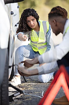 young guy lifting car on jack changing wheel