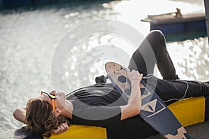 Young guy lying on skateboard spending time at skatepark