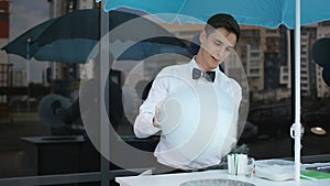Young guy making cotton candy on a special machine, it wears bow tie, behind him balloons