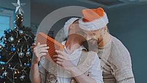 Young guy male couple gifting each other with christmas stockings. Homosexual relationship and winter holidays concept