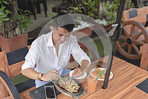 A young guy mixing a platter of yummy and salivating sizzling pork sisig which is a famous Filipino local cuisine