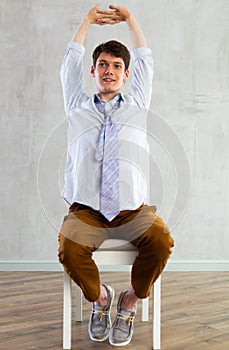 Young guy office worker doing exercises on chair